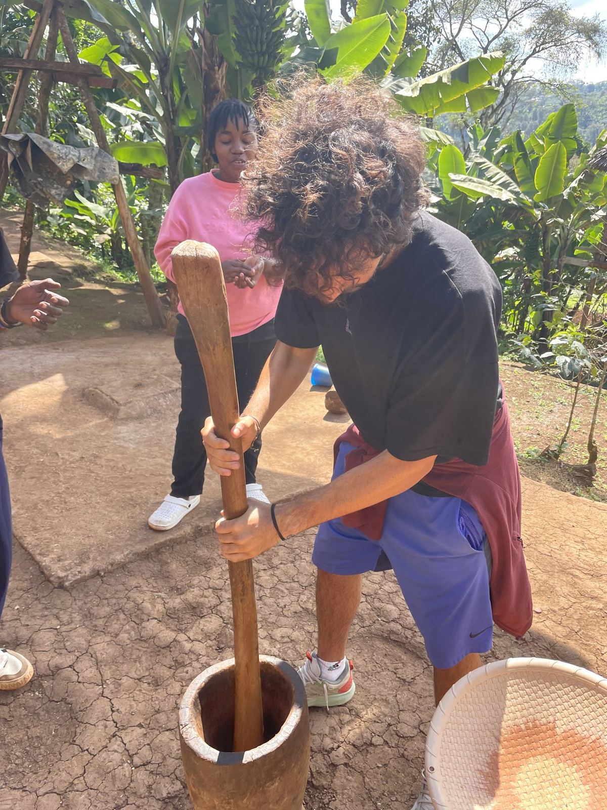 A guest pounding roasted coffee in a wooden mortar